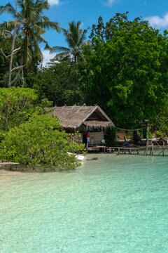Local children by traditional stilt house on tropical lagoon, Indonesia