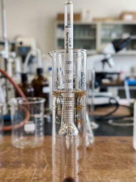 Laboratory glass hydrometer spindle floating in cylinder for liquid density test