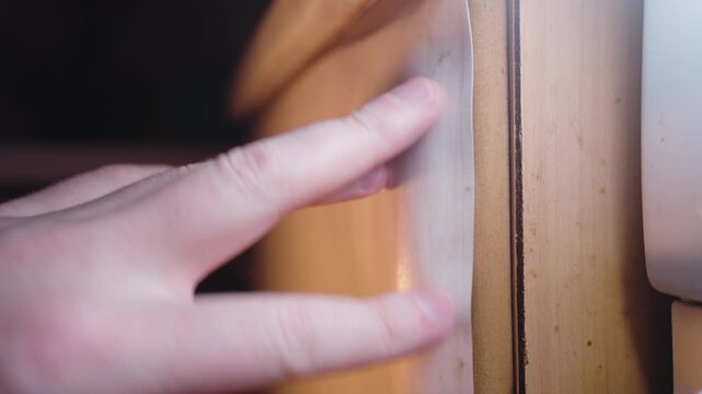 Hand Inspecting Peeled Laminate on Kitchen Cabinet: Close-Up Repair Assessment | Carpenter Checking Delaminated MDF Panel Edge | Furniture Damage Evaluation Detail Shot