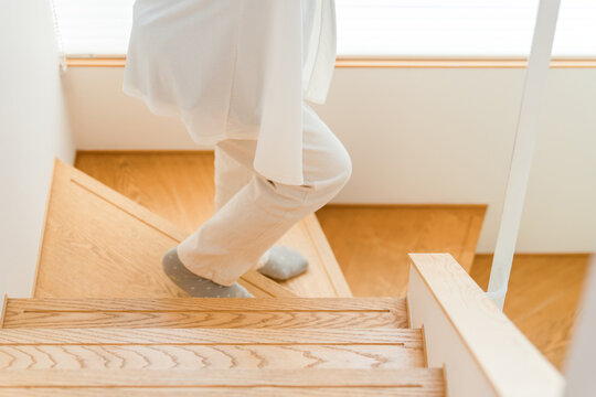 A senior woman descending the stairs of her home.