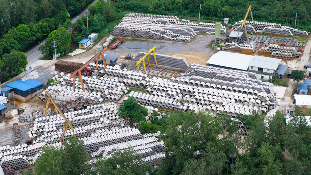 Aerial top‑down view of concrete pipe factory storage yard with industrial machinery