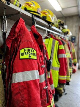 Red First Responder Jacket and Firefighter Gear Hanging in a Fire Station Locker Room, Professional Emergency Service Equipment