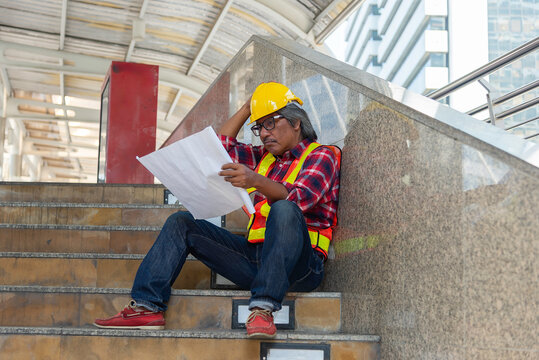 Confident Industrial Worker in Yellow Hardhat Teal Uniform Strong Professional Refinery Background