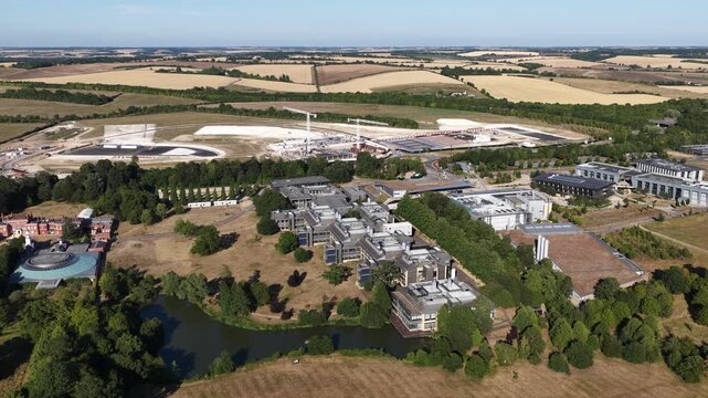 Aerial perspective slowly panning over the wellcome genome campus in hinxton. Cambridgeshire. Showing modern scientific buildings. A tranquil lake