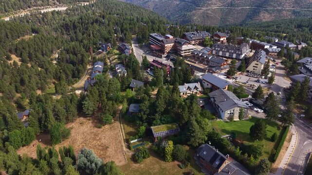 La Molina mountain village in Catalonia, Spain, surrounded by pine forests and Pyrenean slopes, featuring alpine chalets, hotels, and solar panels amid lush summer greenery