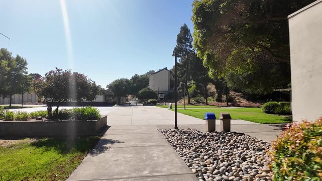 Point of view shot moving forward along a concrete path through the California State University Maritime Academy campus on a sunny day with a clear blue sky in Vallejo, California