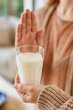 Person refusing a glass of milk with hand gesture, symbolizing dietary restrictions or allergies