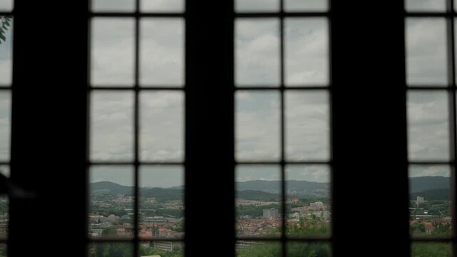 Guimar&atilde;es Portugal city view framed through dark mullioned window panes from hilltop