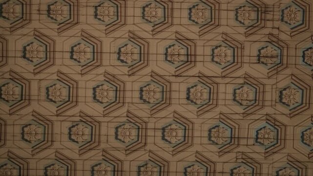 Repeating hexagonal rosette pattern carved into aged wooden ceiling panels