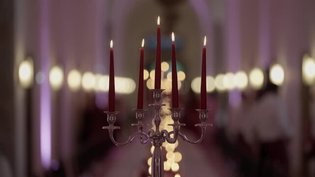 Silver candelabra holding lit red taper candles glowing at elegant evening event