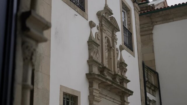 Ornate baroque stone doorway with carved figures and scrollwork on white facade Guimar&atilde;es