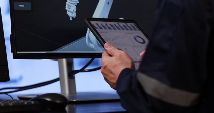 Person holding a tablet with business charts and graphs beside computer monitors in a modern office or control room