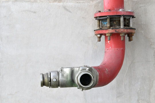 fire department connection pipe on concrete wall, red fire protection piping with metal coupling for supplying water to building sprinkler or standpipe system during firefighting operations