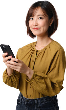 Smiling asian woman holding smartphone with happy expression while standing against clean background in yellow shirt