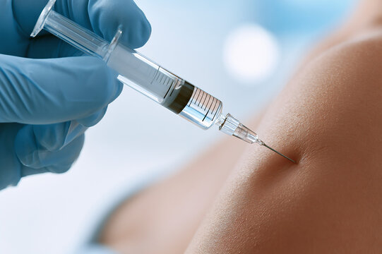 gloved hand depressing a medical syringe into skin