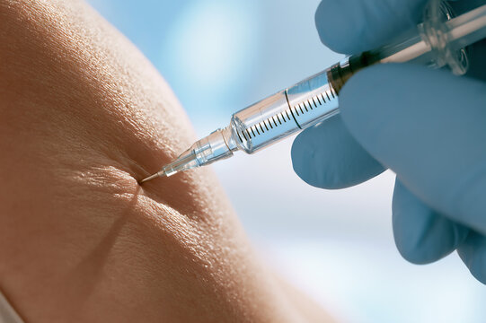 gloved hand depressing a medical syringe into skin