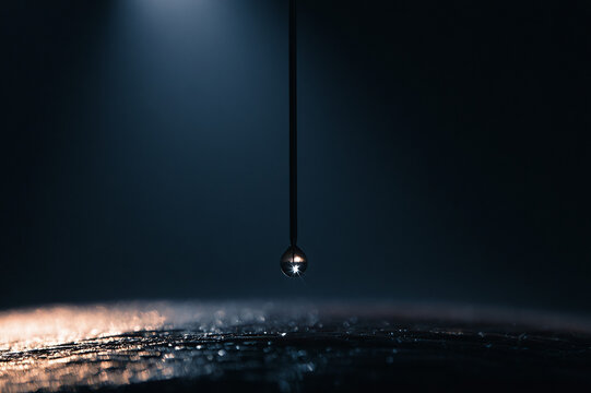 Dramatic low-angle photo of a hypodermic needle preparing for injection under overhead surgical lights