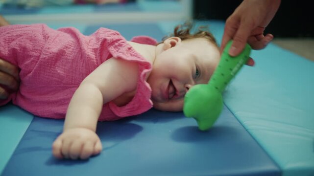 Smiling baby with Down syndrome on a gym mat, enjoying physical therapy, promoting development and happiness