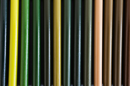 close-up of green and brown colored pencils neatly lined up in pencil case, concept of creativity, drawing, education and art supplies