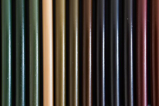close-up of green and brown colored pencils neatly lined up in pencil case, concept of creativity, drawing, education and art supplies