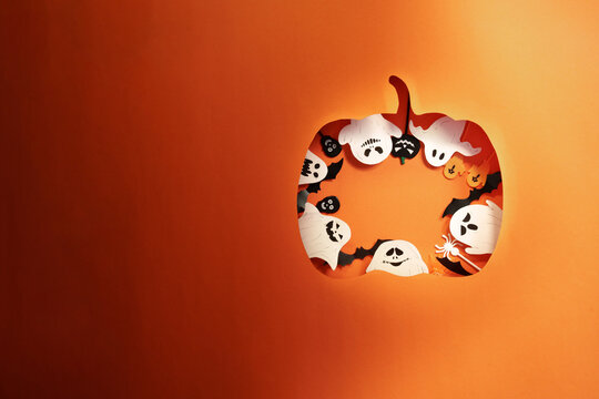 Halloween pumpkin paper cutout with ghosts and bats on orange background