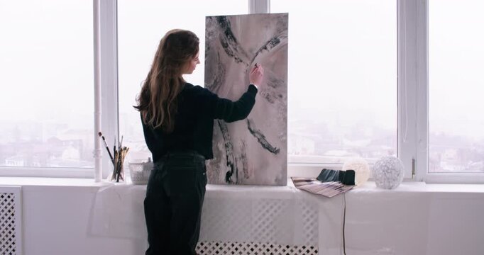 Artist studio. Talented painter. Inspired woman master enjoying hobby creating artwork on canvas at workspace interior.