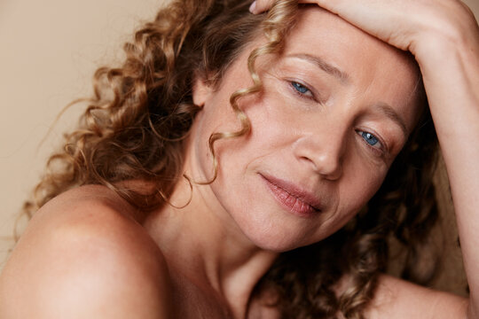 Authentic portrait of a mature woman with natural skin and soft lighting, relaxed pose, warm tones, candid mood, without retouching, beauty in aging and natural confidence.