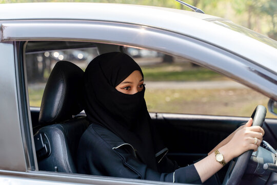 Closeup a beautiful Muslim woman in Abaya niqab traditional clothes driving a car in city
