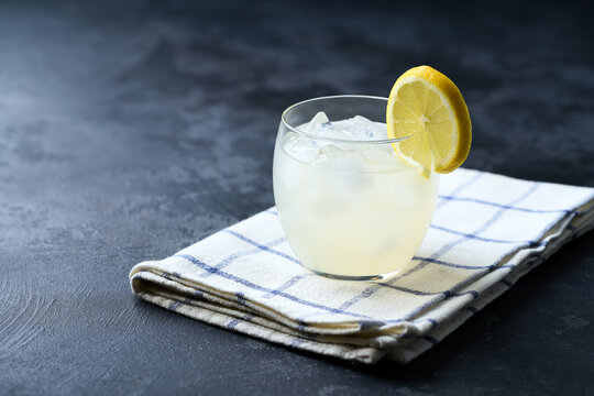 A glass of homemade lemonade on the dark kitchen table. Copy space for text.