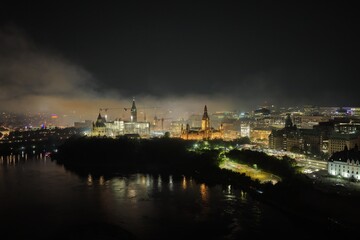 Fototapeta premium Ottawa skyline at night with Parliament Hill, city lights, haze, smog and pollution above the Ottawa River. g.