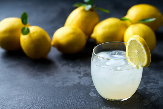 Refreshing homemade summer lemonade in glass with ice on a black table, selective focus. Cold refreshing lemonade .