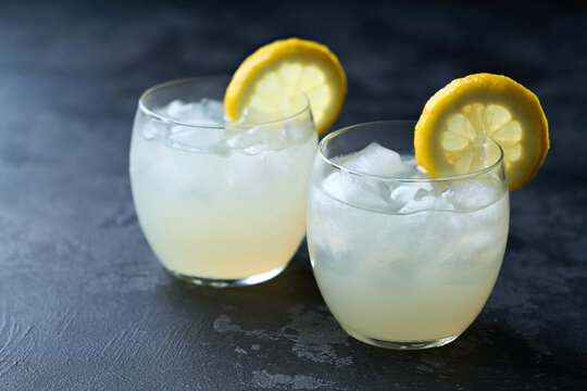 Freshly made lemonade with ice on dark table, selective focus, cold refreshing drink in summer .