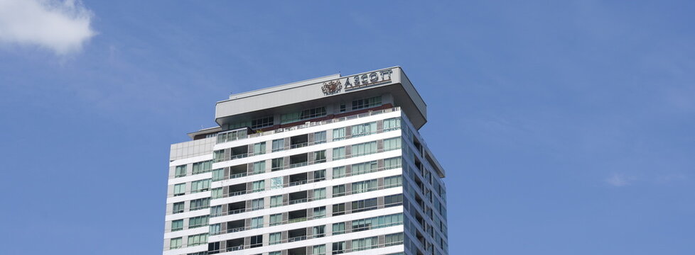 View of the upper levels and rooftop signage of Ascott Sathorn high-rise building against a clear blue sky in Thai capital Bangkok