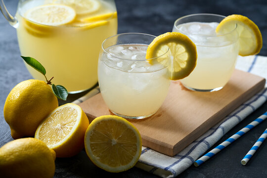 lemonade water with lemon slices , healthy and detox water drink with ice in summer on the dark kitchen table.