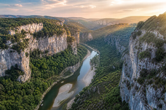 Aerial view of lush green river winding through limestone gorge in France.