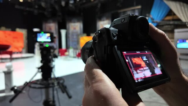 Professional cameraman filming studio production set using mirrorless digital camera for broadcasting project.
