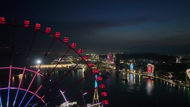 Aerial nighttime view of a glowing ferris wheel beside the illuminated waterfront in Ha Long, Quang Ninh, Vietnam.