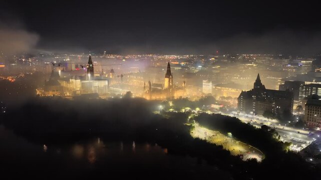 Ottawa skyline at night with Parliament Hill, city lights, haze, smog and pollution above the Ottawa River. g.