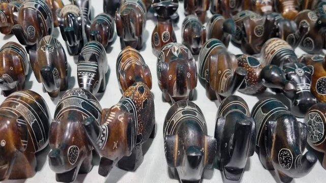 Rows of hand-carved animal figurines are displayed for sale at a local market in Djanet, Algeria, showcasing Tuareg-inspired craftsmanship and traditional souvenirs in the heart of the Sahara