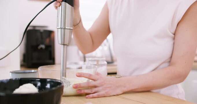 Blending food. Preparing meal. Woman chef hand mixing white cottage cheese in bowl on kitchen countertop with modern electric equipment.