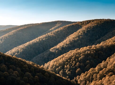 Rugged mountain ridges with orange and dark brown soil under a clear blue sky