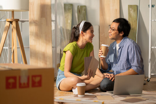 Asian couple of home owners discussing new renovate home,wood samples,moving box,interior design improvement,new design for new home.asian chooses a sample floor for his new apartment