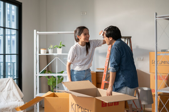 Asian couple of home owners discussing new renovate home,wood samples,moving box,interior design improvement,new design for new home.asian chooses a sample floor for his new apartment