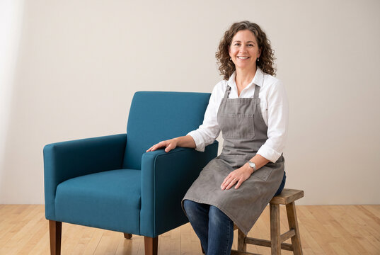 Confident Furniture Upholsterer Sitting Beside His Restored Armchair