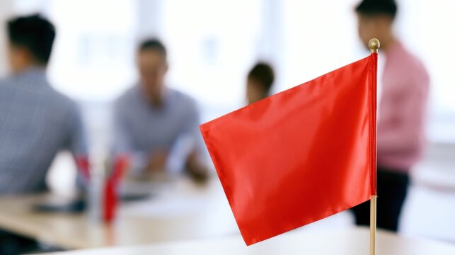 Meeting room discussion with red flag in focus and blurred people in the background
