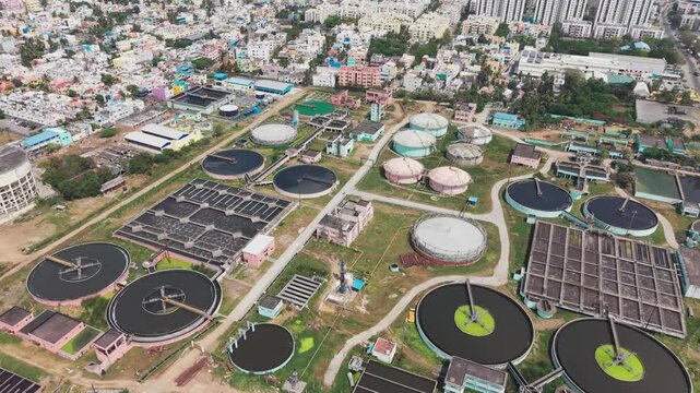 Wide Aerial view of sewage treatment plant showing tanks lined up next to residential area