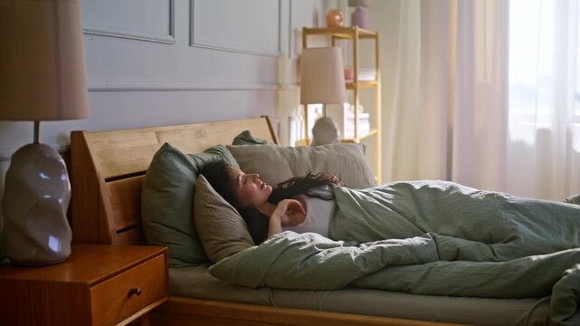 Pregnant female waking up cozy bed morning. Expecting mother stretching home.