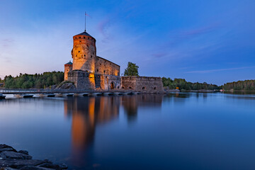 Olavinlinna Castle Illuminated at Dusk over Lake Saimaa in Savonlinna, Finland © Artem