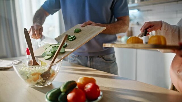 Expecting parents preparing vegetable salad kitchen. Closeup hands chopping.