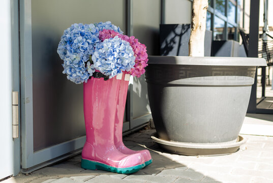 Beautiful flowers inside an ornamental plastic boot at a street.
